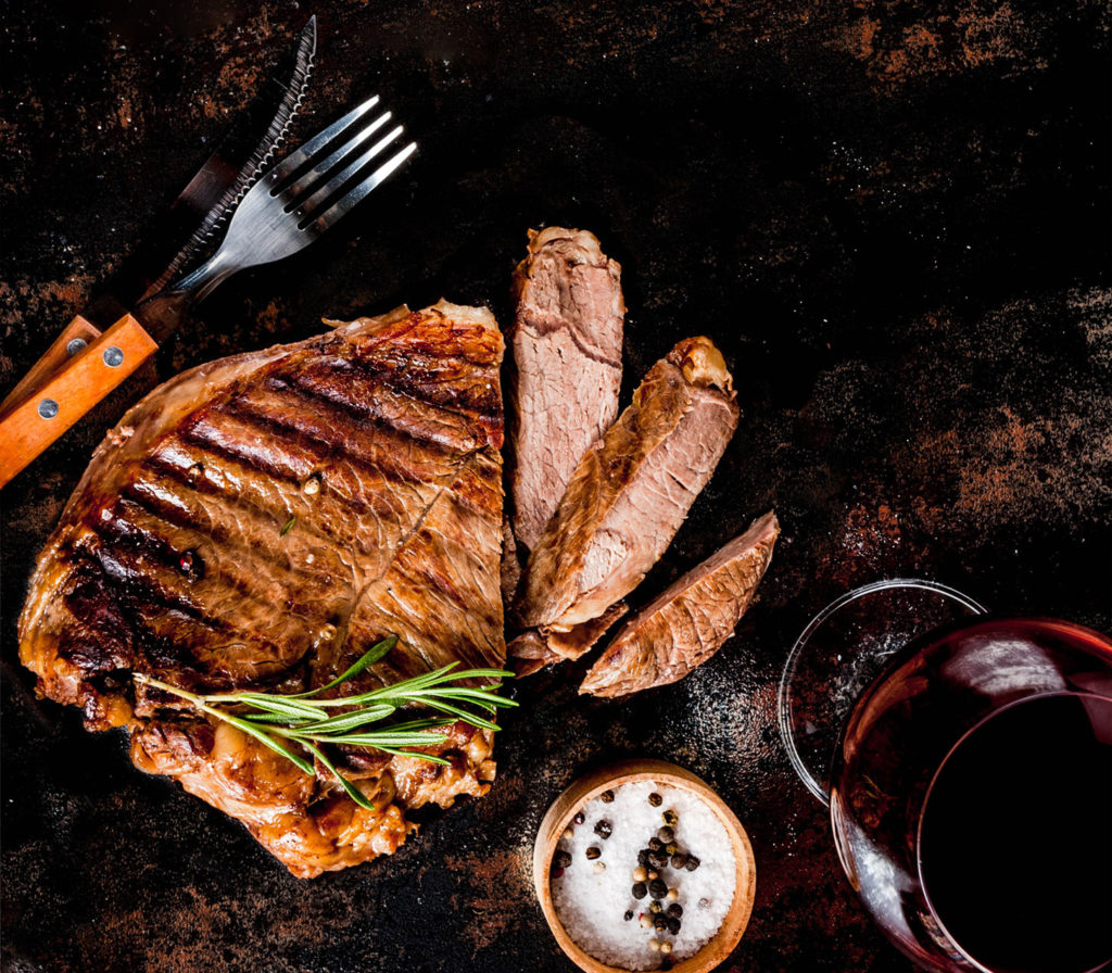 grilled beef steak with spices on grill pan board, with and red