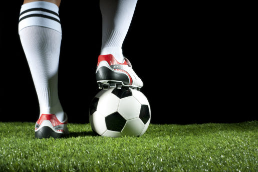 Man standing with one foot on a soccer ball