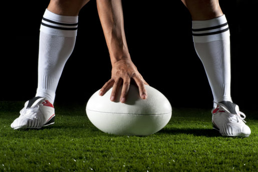 Close up of a man playing a rugby ball at night